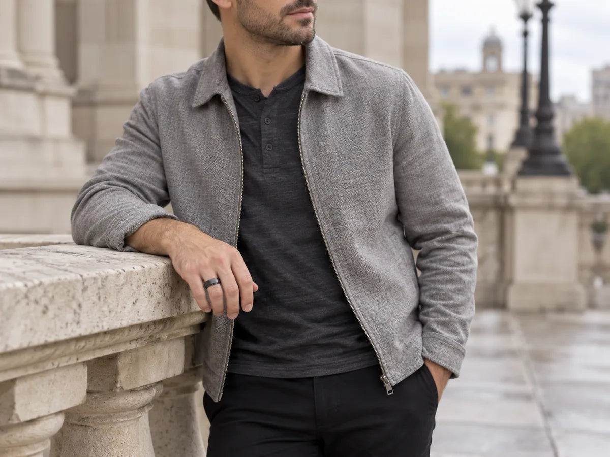 Man wearing a brushed black tungsten ring beside a stone railing.