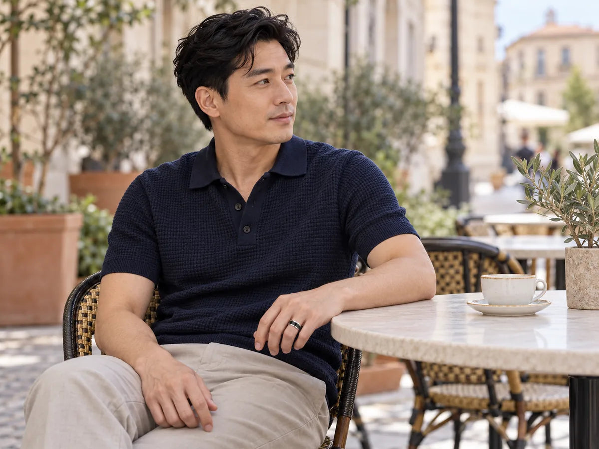 Man wearing a stainless steel ring with black ceramic inlay on a cafe terrace.